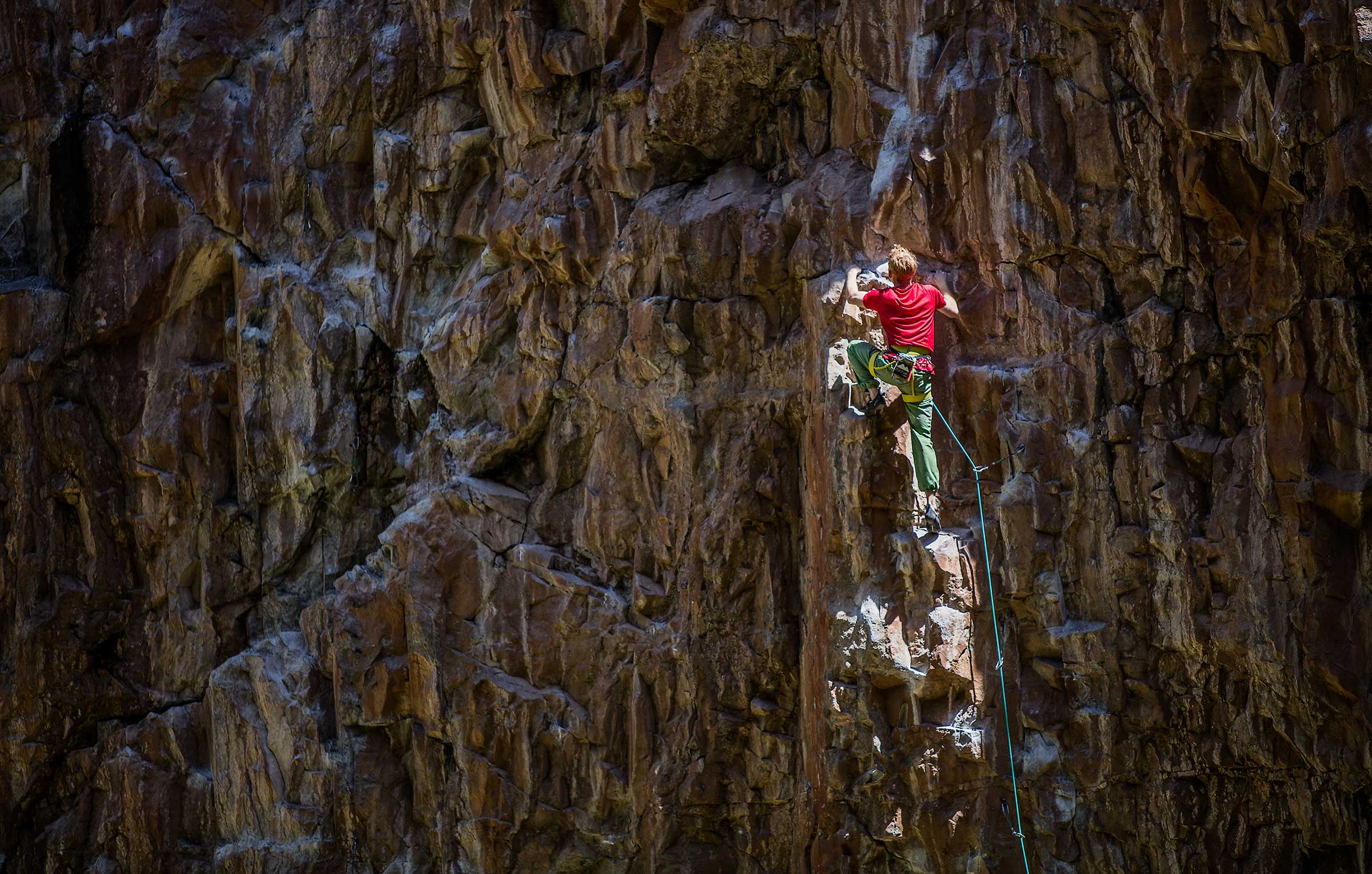 A professional rock climber illuminated by a dramatic shaft of light in Colorado