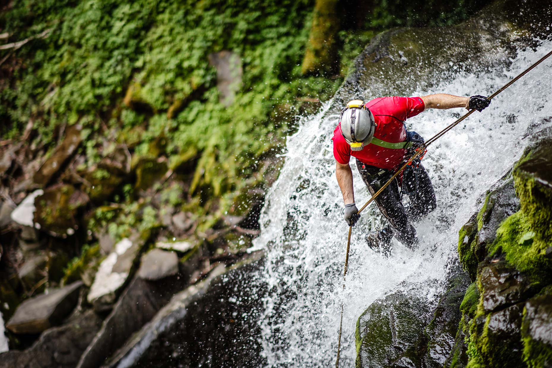 A canyoneer rappels down a powerful raging waterfall in the Catskills New York
