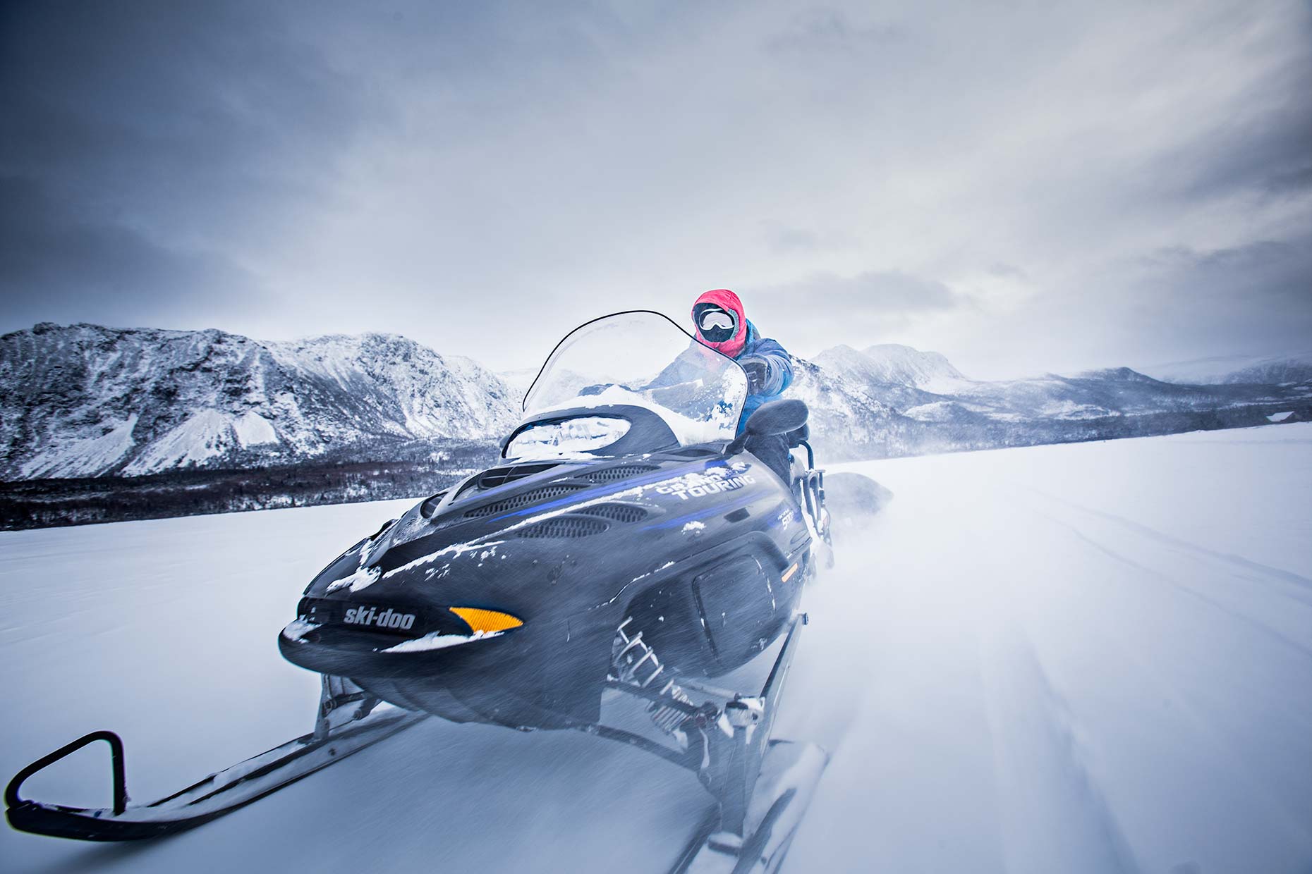 motion blurred closeup of ice climber driving snowmobile in remote snowy location