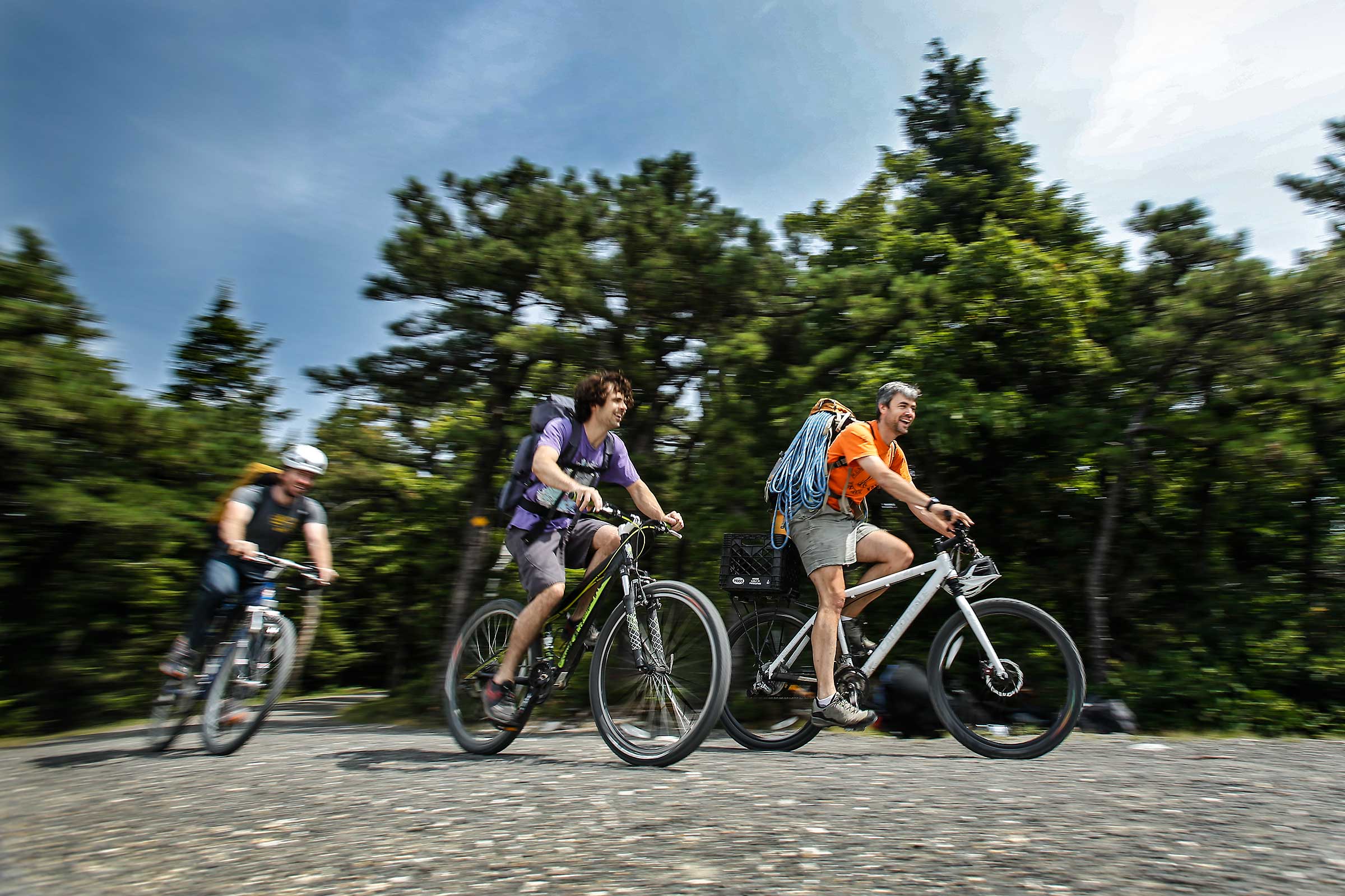 Three men with rock climbing equipment riding mountain bikes in Shawagunks New York