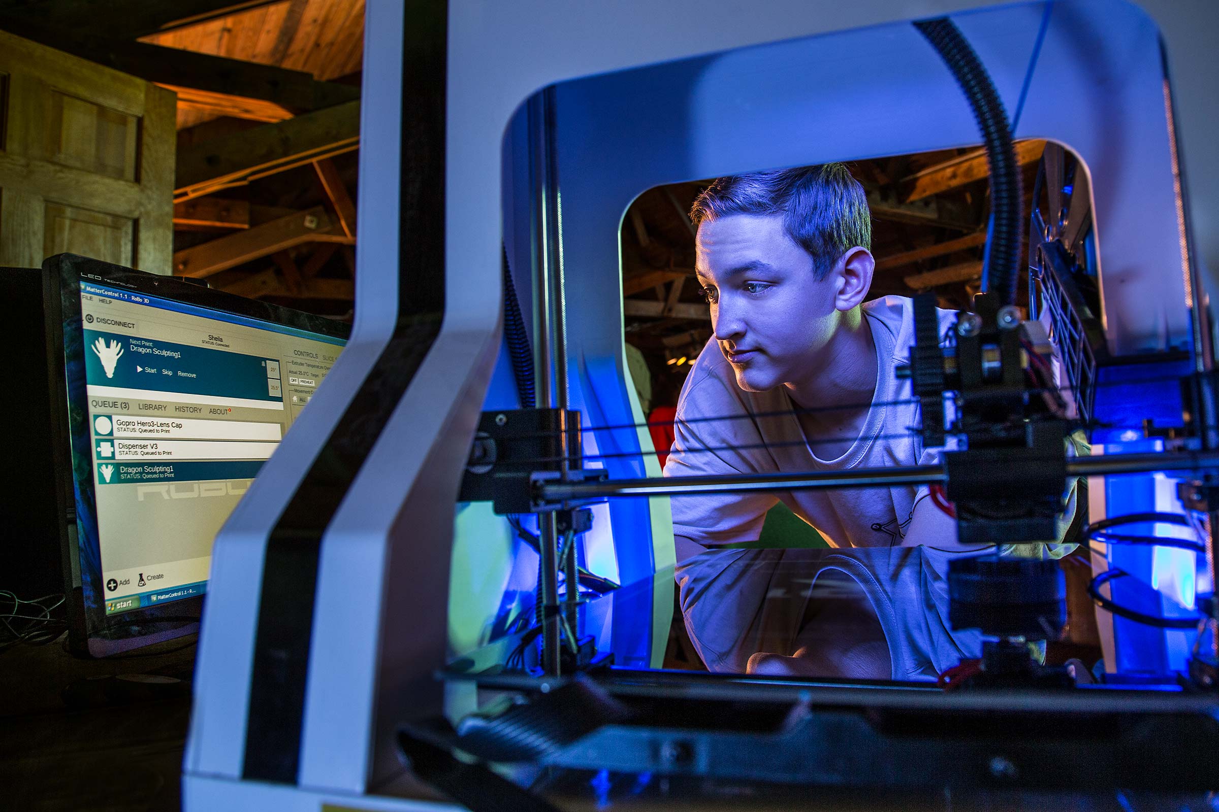 A teenage boy workign with a 3D printer in a STEM technologies program