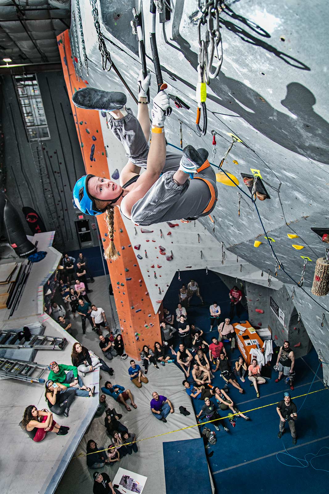 A young professional female ice climber competing in an indoor ice climbing contest