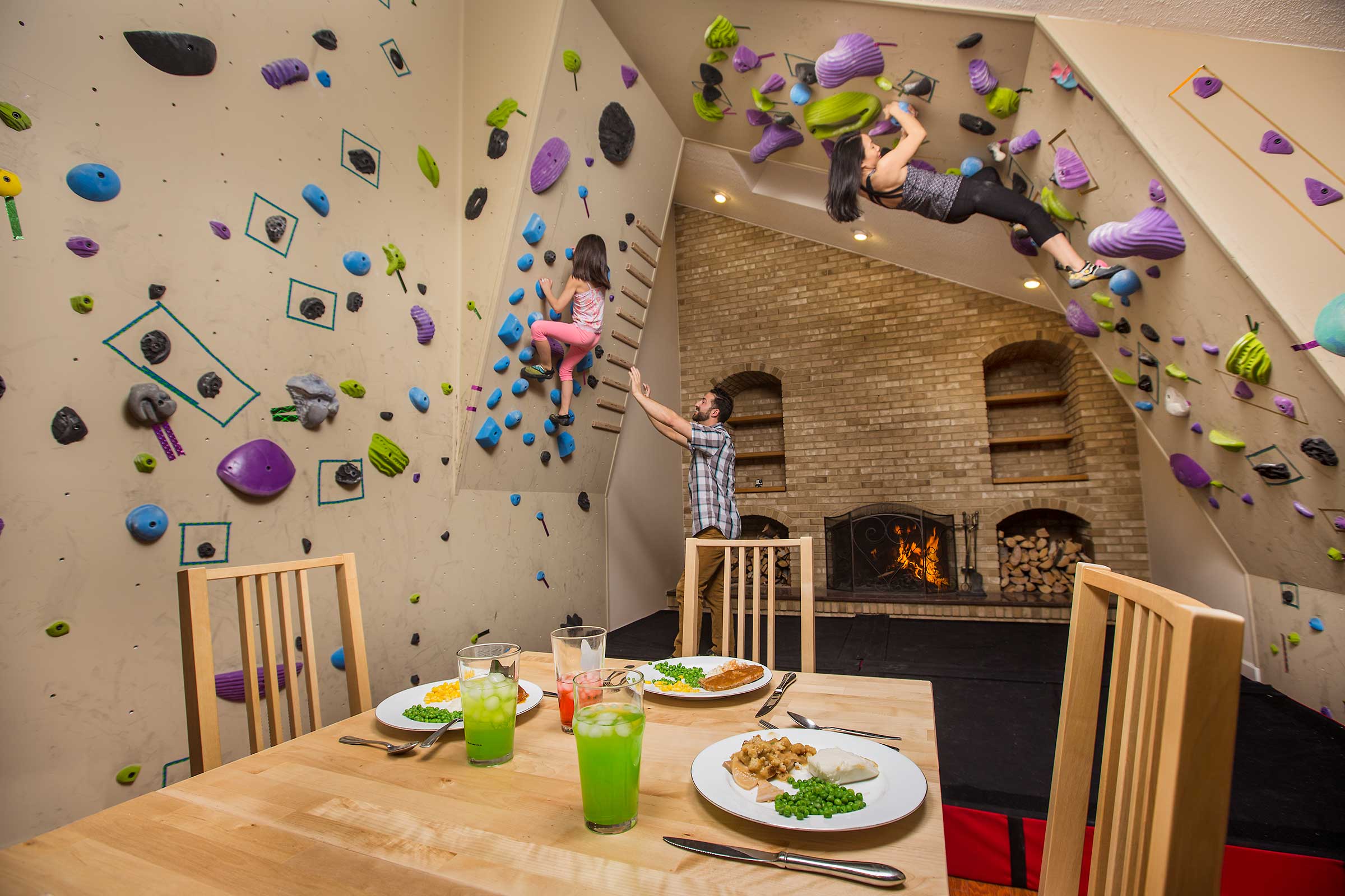A multiracial family rock climbing in their living room 