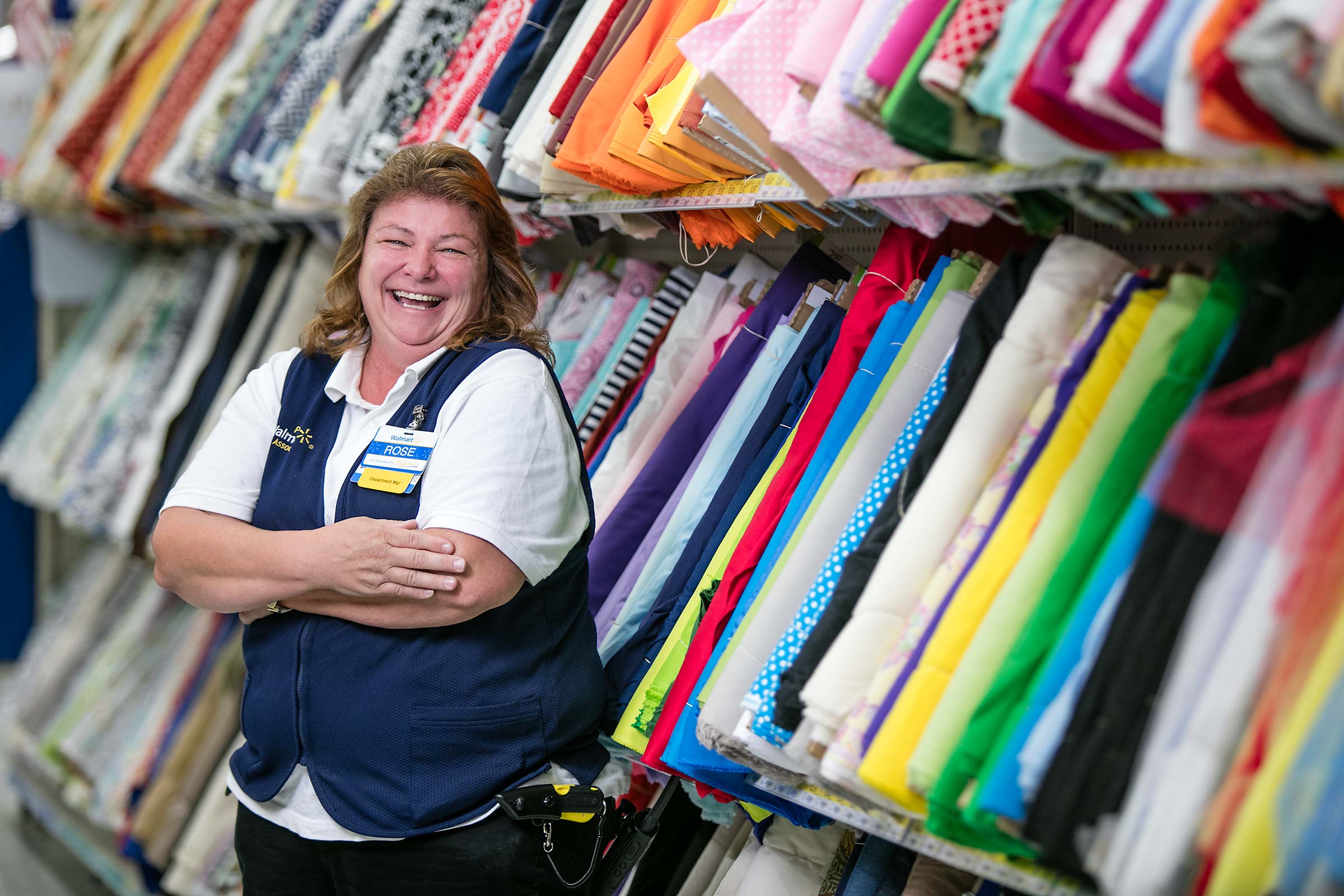 A retail employee laughing in a store aisle while at work