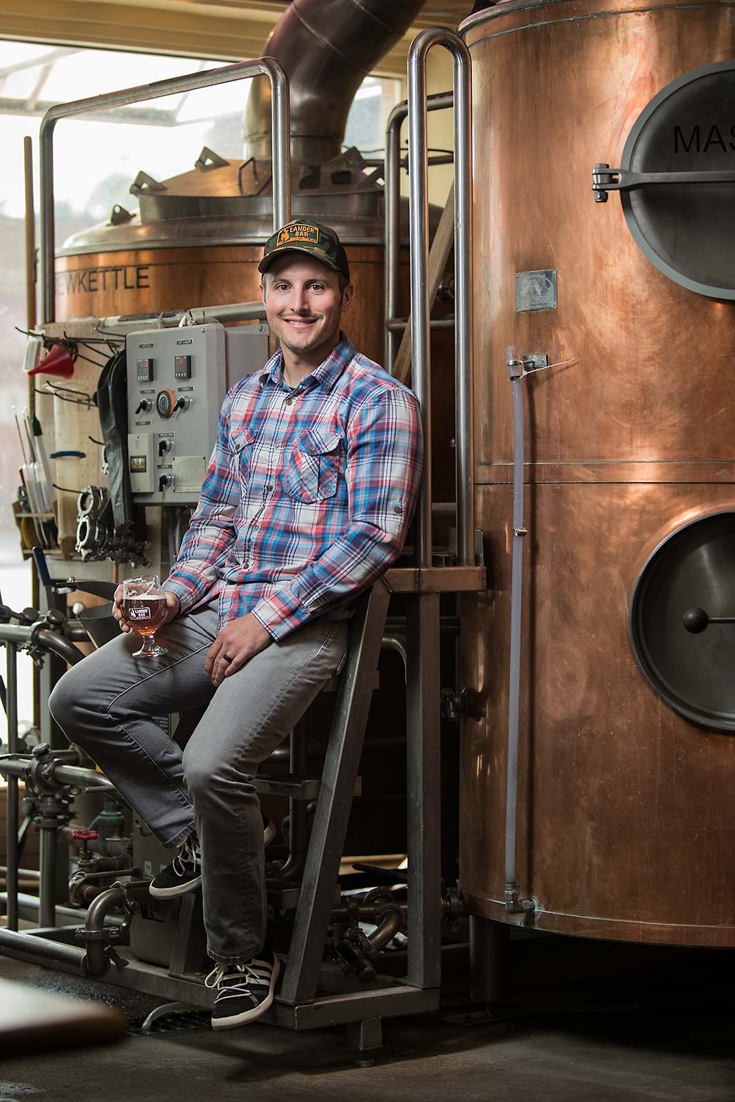 A brewmaster and resturant owner smiles next to his brewing facility ...