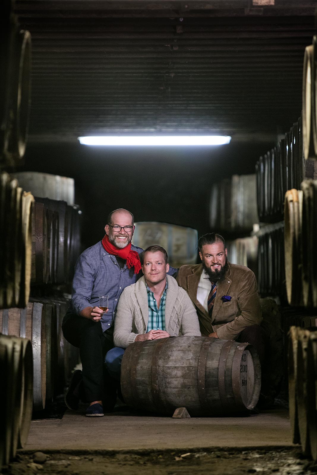 Young entrepreneurs pose near a whiskey barrel at a distillery in Islay Scotland