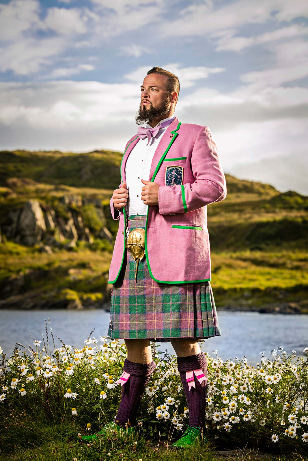A location portrait of a  man in fashionable kilt amid flowers in Scotland
