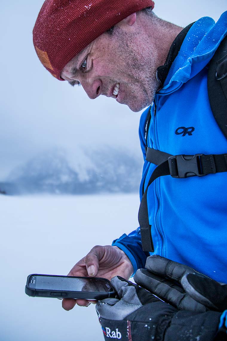 closeup of a man navigating with GPS in remote winter location during storm