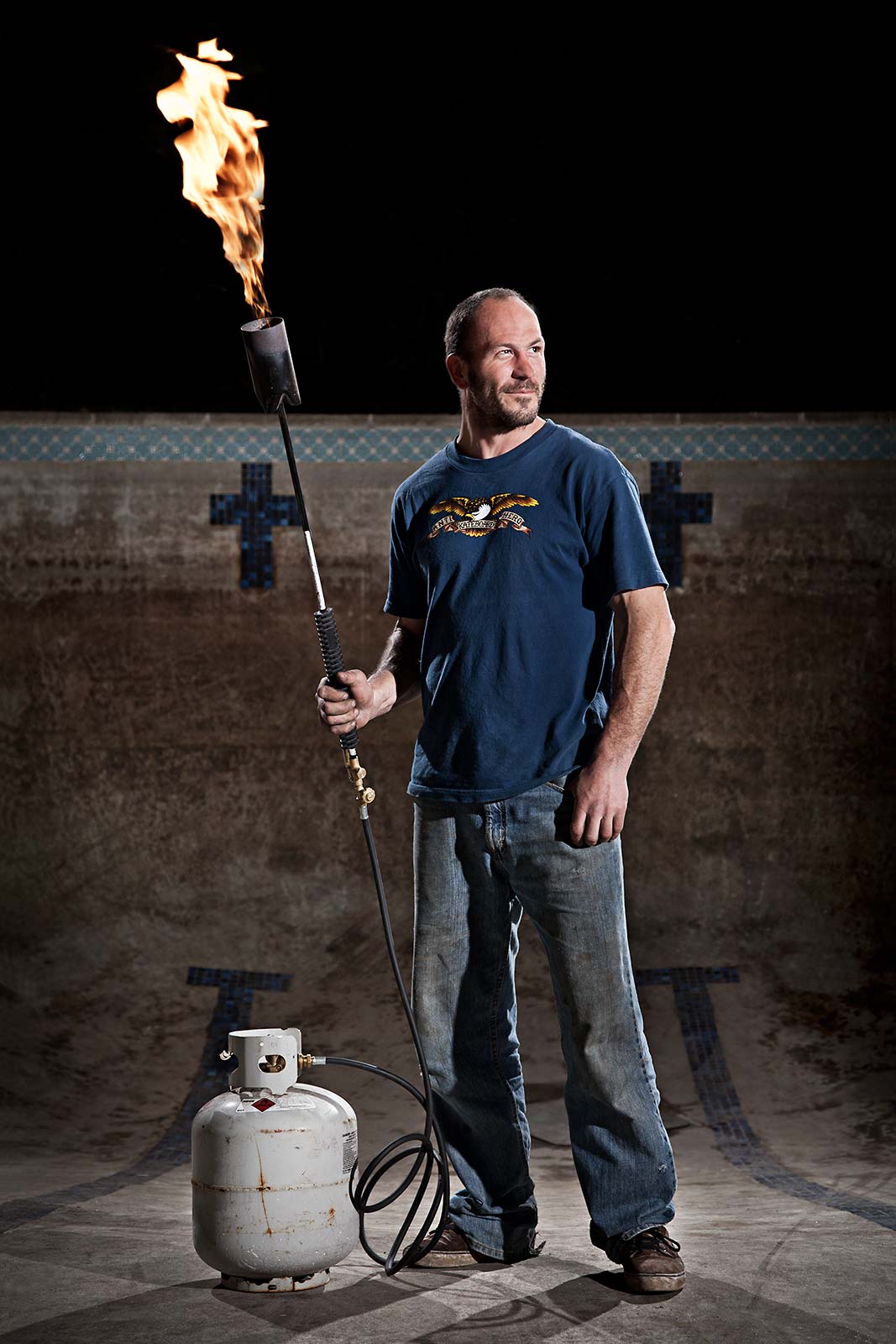 Portrait of a man wielding a torch in an empty swimming pool in Connecticut