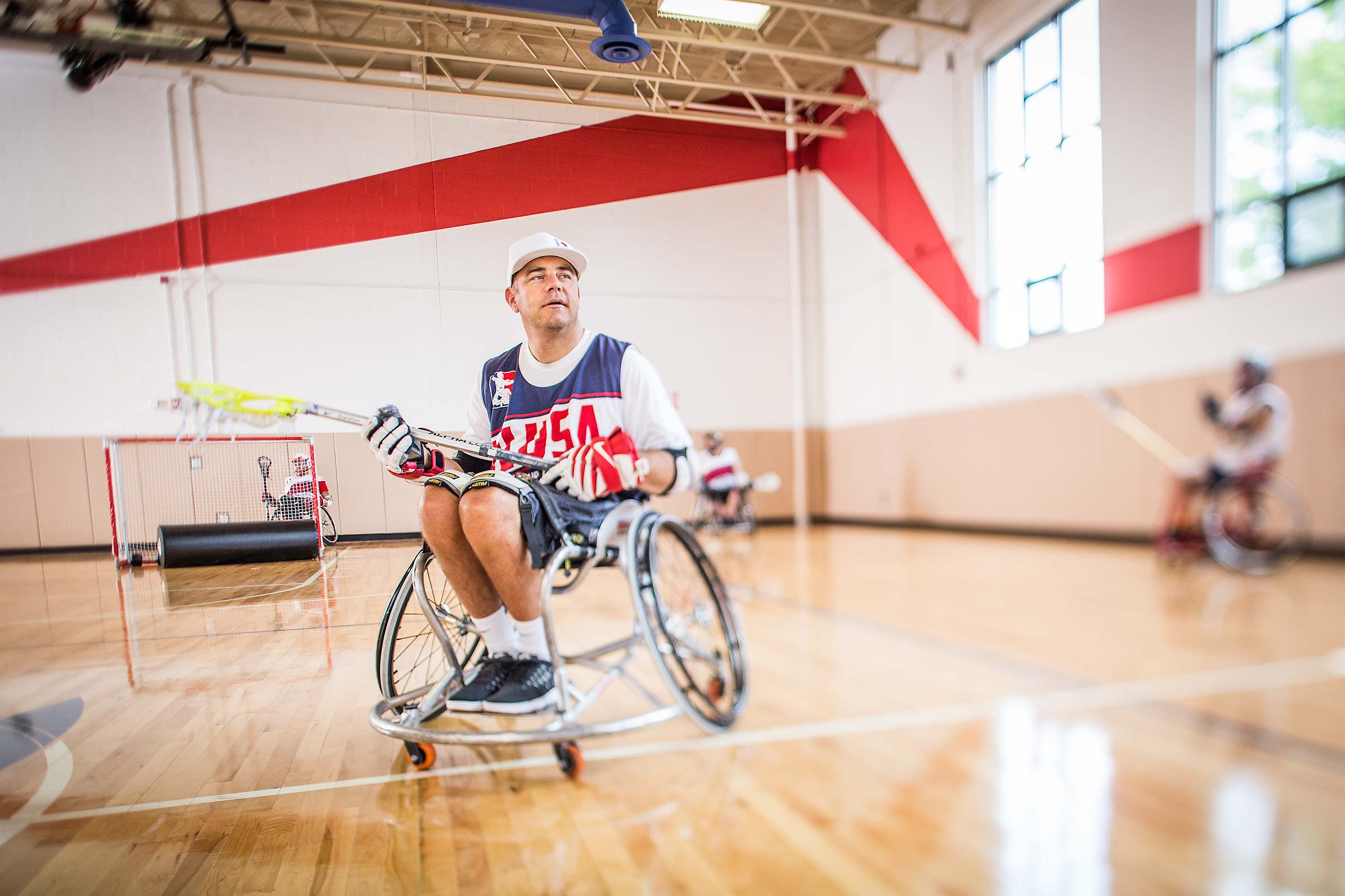 Wheelchair lacrosse founder throwing ball on an indoor court in Connecticut