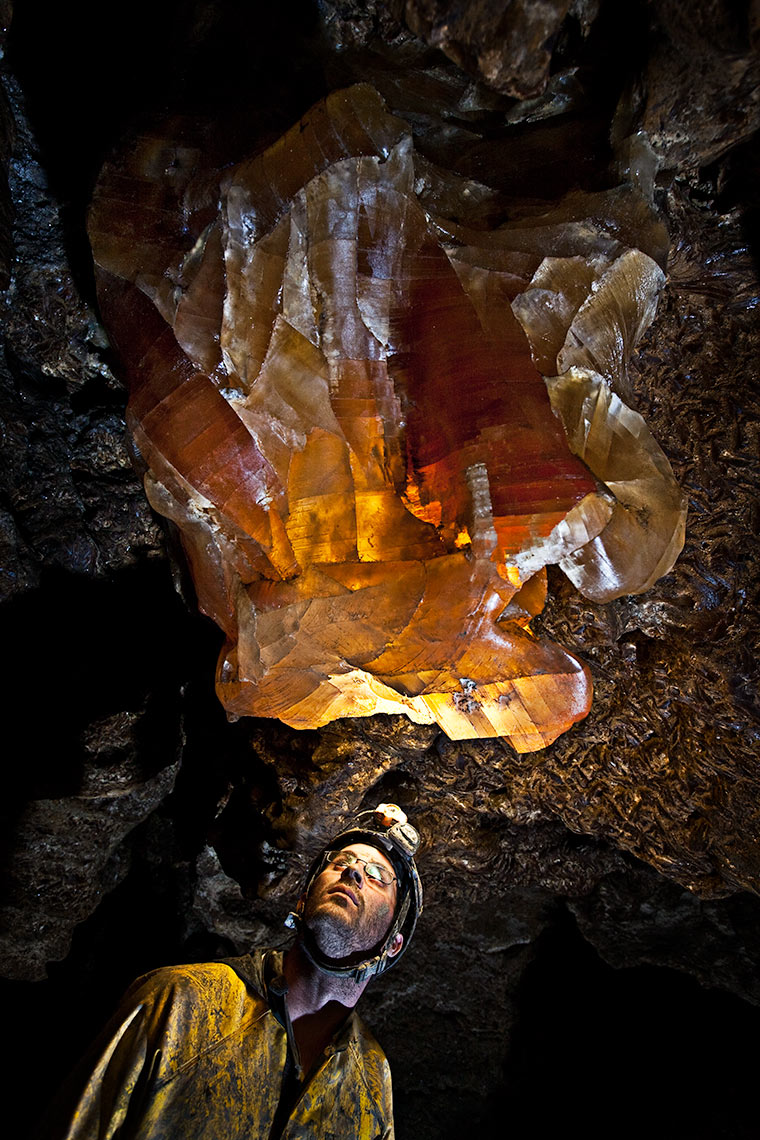 A caver inspects a glowing giant gypsum crystal in a labyrinth cave system in Ukraine 