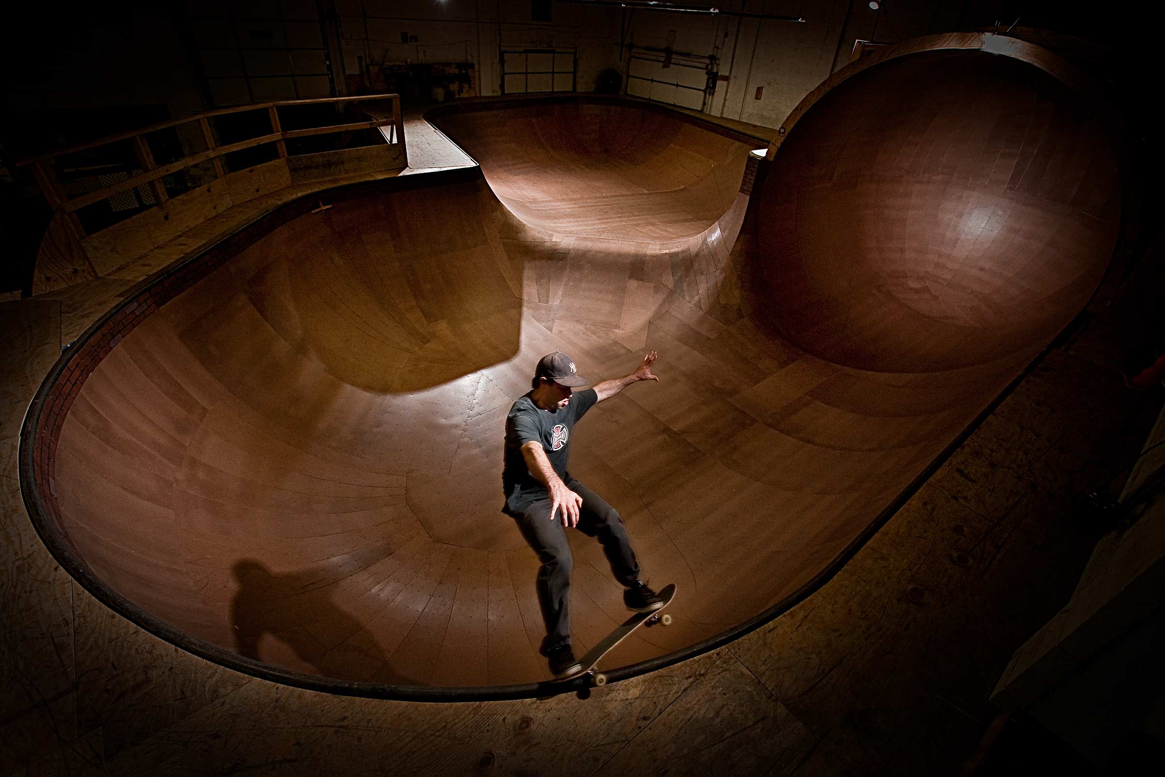 A dramatically lit action shot of a man skateboarding at an indoor park in Connecticut