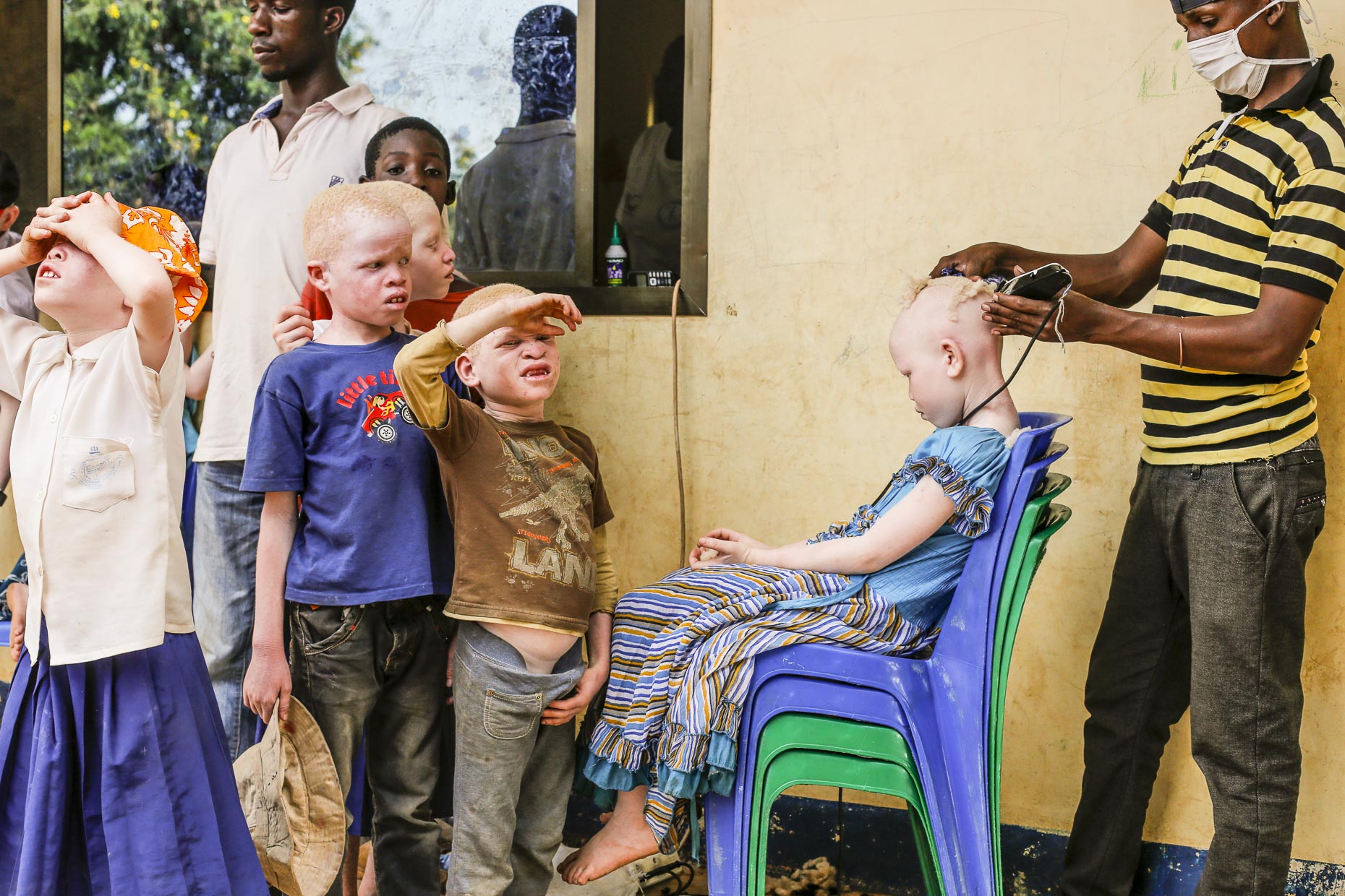 A group of children line up to have their heads shaved in an orphange for albinos in East Africa